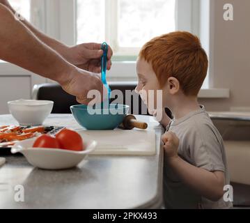 L'enfant examine la nourriture sur l'assiette. Banque D'Images