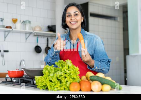 Femme hispanique préparant des aliments végétariens ou végétaliens avec des tomates et des pommes de terre et de la salade Banque D'Images