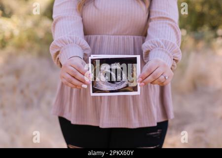 Femme enceinte non reconnaissable tenant des jumeaux échographiques Banque D'Images