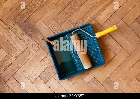 brosse et rouleau dans un récipient avec vernis pendant le vernissage du parquet Banque D'Images