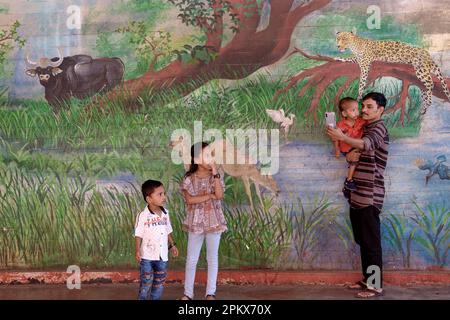 Un père prend des selfies avec ses enfants lors d'une fresque à la gare de Byculla à Mumbai, en Inde, son thème de la faune est un hommage au zoo voisin de Byculla Banque D'Images