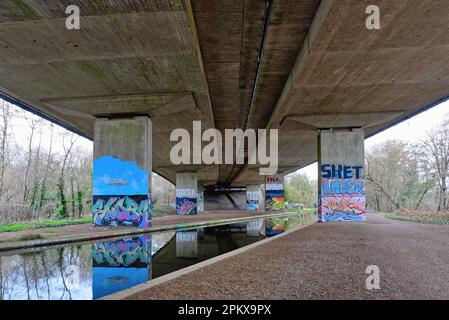 Graffiti peint sur des colonnes soutenant le pont de M25 qui le transporte au-dessus du canal de la rivière Wey à New Haw Surrey, Angleterre, Royaume-Uni Banque D'Images