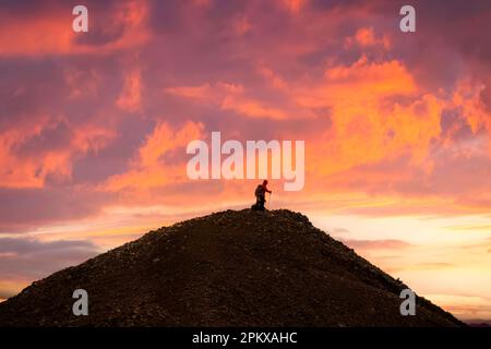 Groupe de randonneurs se tenant au sommet de la montagne volcanique avec un ciel coloré au coucher du soleil parmi les Highlands islandais en été à l'Islande Banque D'Images