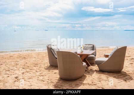 Chaise en rotin avec coussin et table sur la plage par la mer tropicale par jour ensoleillé Banque D'Images