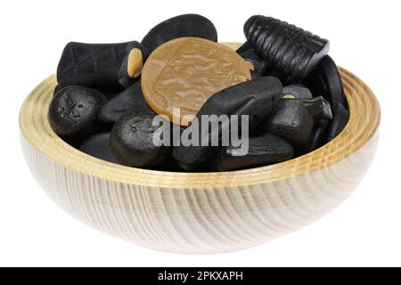 Bonbons de réglisse hollandais dans un bol en bois isolé sur fond blanc Banque D'Images