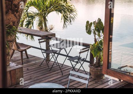 Table et chaises en bois vides sur le patio dans le jardin tropical au bord du lac à la campagne Banque D'Images