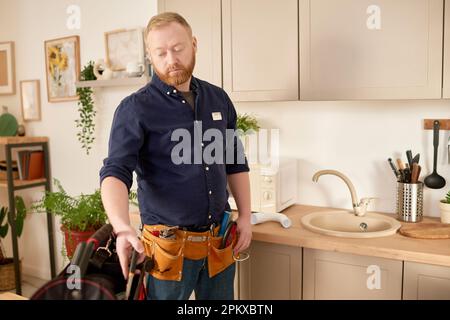 Réparateur utilisant des outils de travail pour fixer l'évier et le robinet pendant son travail dans la cuisine domestique Banque D'Images