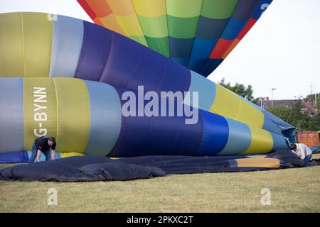 Les gens travaillent pour dégonfler, rouler et emballer des ballons d'air chaud qui viennent d'atterrir Banque D'Images