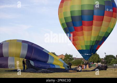 Les gens travaillent pour dégonfler, rouler et emballer des ballons d'air chaud qui viennent d'atterrir Banque D'Images