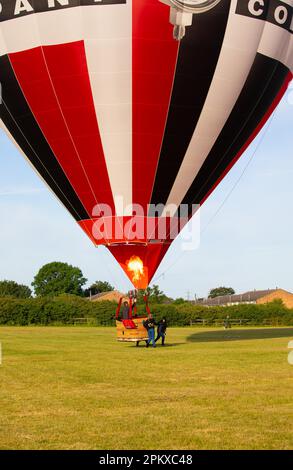 Les gens tirent le long d'un ballon d'air chaud gonflé pour qu'ils puissent le prendre à un meilleur endroit pour le délasser, le rouler et l'emballer. Banque D'Images