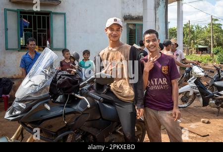 Deux jeunes hommes appartenant à la minorité ethnique de Jerai se posent à côté d'une grande moto IA Pia, dans les Hautes-terres centrales du Vietnam. Banque D'Images