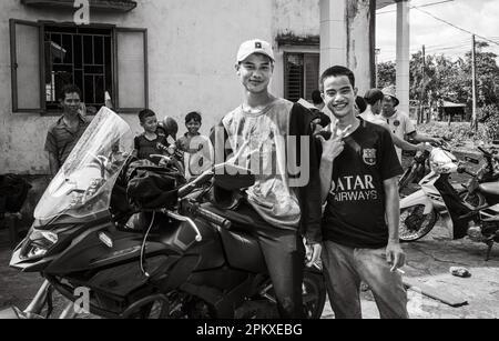 Deux jeunes hommes appartenant à la minorité ethnique de Jerai se posent à côté d'une grande moto IA Pia, dans les Hautes-terres centrales du Vietnam. Banque D'Images