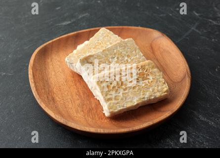 Tempe ou tempeh bruts tranchés sur une assiette en bois. Tempeh est Superfoods, alternative à la viande, sources de protéines, probiotiques Banque D'Images
