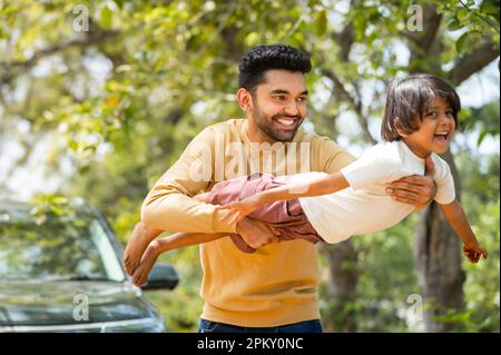 Joyeux jeune père jouant en tenant sa fille pendant que l'enfant vole comme un avion - concept de bien-être émotionnel, Voyage de week-end et de la parentalité Banque D'Images