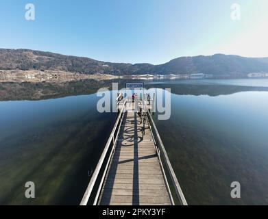 Une jetée en bois idyllique qui s'étend sur les eaux bleues étincelantes d'Ossiacher See en Carinthie, en Autriche, par une journée ensoleillée Banque D'Images