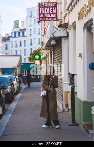 Jeune belle femme porte un manteau et sac de côté blanc - regarde l'appareil photo - Paris, France Banque D'Images