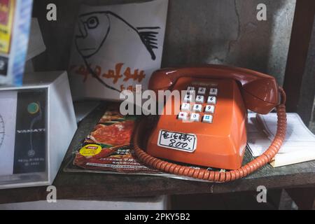 Téléphone rouge vintage avec autocollant d'écriture japonais et magazines japonais sur l'étagère Banque D'Images