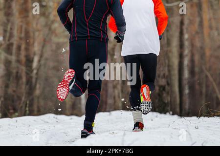 jambes deux coureurs piste enneigée en forêt, semelles chaussures de course mâle athlète hiver course Banque D'Images