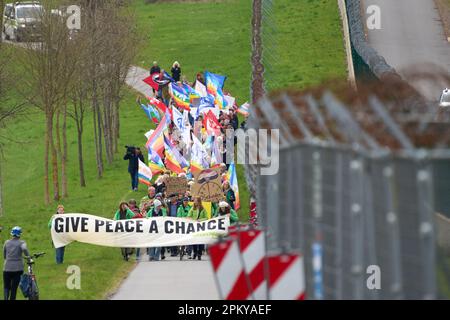 10 avril 2023, Rhénanie-Palatinat, Büchel : les participants à la marche de Pâques marchent à côté de la clôture de la base aérienne de Bundeswehr à Büchel. En 2023, de nombreuses marches de Pâques ont également eu lieu à travers l'Allemagne sous l'impression de la guerre de la Russie contre l'Ukraine. Photo: Thomas Frey/dpa Banque D'Images