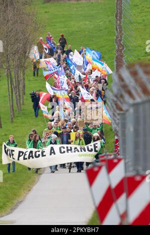 10 avril 2023, Rhénanie-Palatinat, Büchel : les participants à la marche de Pâques marchent à côté de la clôture de la base aérienne de Bundeswehr à Büchel. En 2023, de nombreuses marches de Pâques ont également eu lieu à travers l'Allemagne sous l'impression de la guerre de la Russie contre l'Ukraine. Photo: Thomas Frey/dpa Banque D'Images