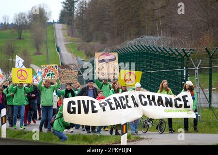 10 avril 2023, Rhénanie-Palatinat, Büchel : les participants à la marche de Pâques marchent à côté de la clôture de la base aérienne de Bundeswehr à Büchel. En 2023, de nombreuses marches de Pâques ont également eu lieu à travers l'Allemagne sous l'impression de la guerre de la Russie contre l'Ukraine. Photo: Thomas Frey/dpa Banque D'Images