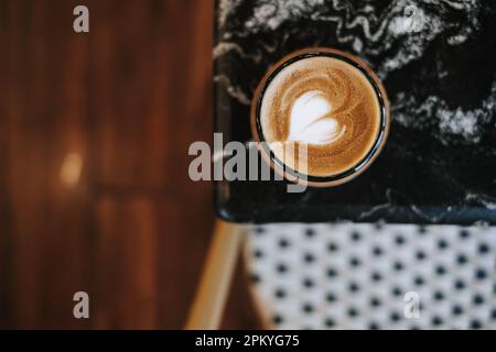 Plan à plat ou vue de dessus photo d'une tasse de café avec un Latte Art simple et magnifique sur une table en marbre noir. Arrière-plan flou. Banque D'Images