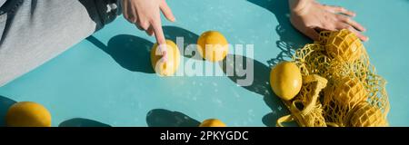 vue courte d'une femme assise près d'un sac à ficelle et de citrons mûrs sur une bannière bleue Banque D'Images