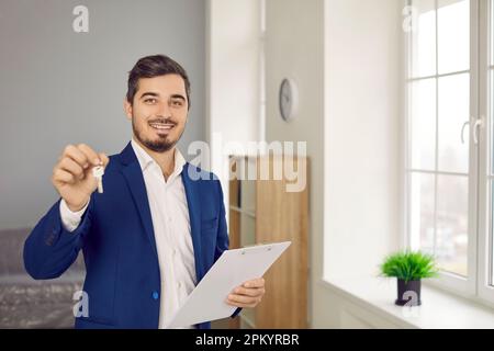 Portrait d'un jeune agent immobilier souriant ou d'un propriétaire qui offre d'obtenir la clé d'un nouvel appartement ou d'une nouvelle maison. Banque D'Images