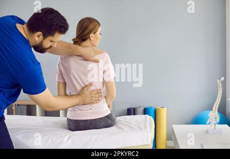 Un physiothérapeute professionnel traite la douleur de la colonne vertébrale de la jeune femme dans une clinique médicale moderne. Banque D'Images