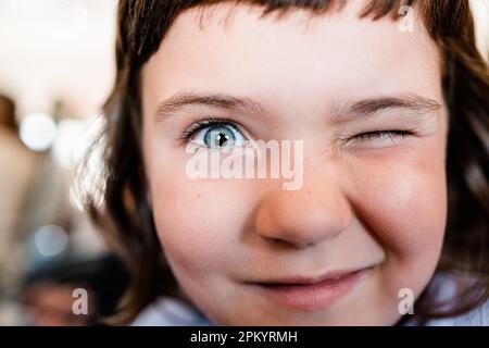 Portrait d'une jeune fille d'âge préscolaire drôle avec des taches de rousseur et des yeux bleus qui se plient à l'appareil photo et sourient sur un arrière-plan flou Banque D'Images
