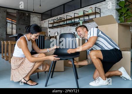 Couple dans des vêtements décontractés focalisés d'assemblage de chaise tout en se déplaçant ensemble à l'appartement nouveau moderne Banque D'Images