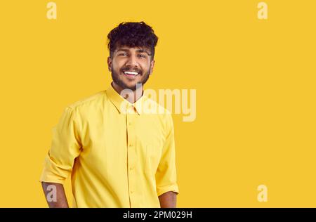 Portrait d'un jeune indien ou arabe souriant, isolé sur fond orange. Banque D'Images