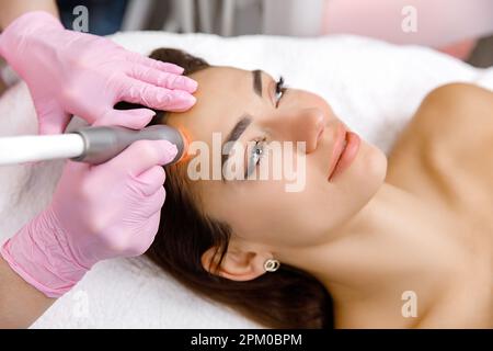 Procédures cosmétiques, soin du visage, traitement de rajeunissement. la femme a une procédure cosmétique du visage avec un cosmétologue. La photo est un gros plan Banque D'Images
