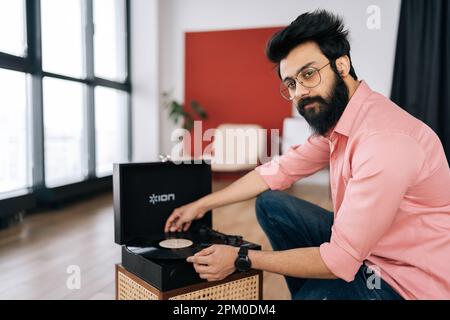 Portrait de beau barbu hipster mâle tête de réglage ancien lecteur de disques et vinyle disques regardant l'appareil photo. Amant de la musique homme à l'écoute de classique Banque D'Images