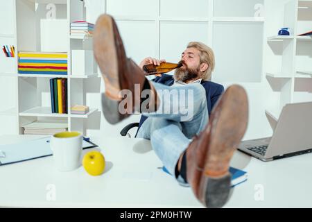 Homme d'affaires buvant de la bière. Homme élégant et stylé de style classique tenant la bière à la main. Pause détente. Homme ivre dans le bureau d'affaires. Travail d'alésage Banque D'Images