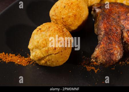 Cuisse de canard rôti très sain avec des pommes de terre et des légumes verts sur une assiette noire sur une table en bois servant dans un restaurant. gros plan canard et pommes de terre Banque D'Images