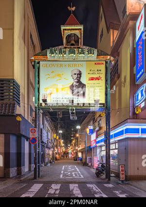 nagasaki, kyushu - déc 11 2022: Porte de la rue commerçante ekimae rouillée et surmontée d'un clocher avec une girouette au-dessus d'un po publicitaire Banque D'Images