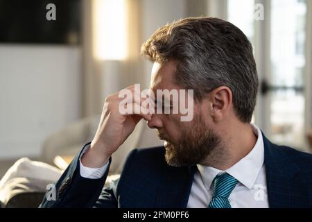 Fatigue, maux de tête et fatigue oculaire depuis un ordinateur portable. Homme d'affaires avec le stress, l'épuisement et la fatigue eyestrain. Homme d'affaires frottant les yeux fatigués après l'ordinateur Banque D'Images