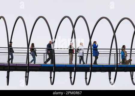 Oberhausen, NRW, le 10th avril 2023. Les randonneurs apprécient un lundi de Pâques plutôt ensoleillé et doux sur le célèbre pont 'linky Springs to Fame' d'Oberhausen. Le pont piétonnier, long de 406 mètres et traversant le canal Rhin-Herne, a été conçu par l'artiste Tobias Rehberger. Il est illuminé la nuit et aurait été inspiré par le jouet slinky. Credit: Imagetraceur/Alamy Live News Banque D'Images