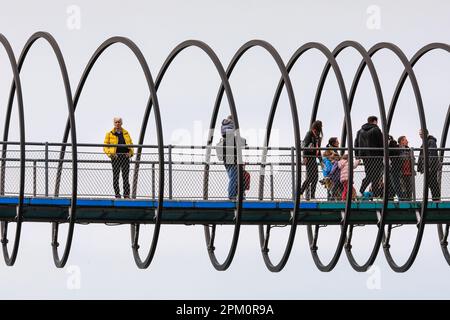 Oberhausen, NRW, le 10th avril 2023. Les randonneurs apprécient un lundi de Pâques plutôt ensoleillé et doux sur le célèbre pont 'linky Springs to Fame' d'Oberhausen. Le pont piétonnier, long de 406 mètres et traversant le canal Rhin-Herne, a été conçu par l'artiste Tobias Rehberger. Il est illuminé la nuit et aurait été inspiré par le jouet slinky. Credit: Imagetraceur/Alamy Live News Banque D'Images