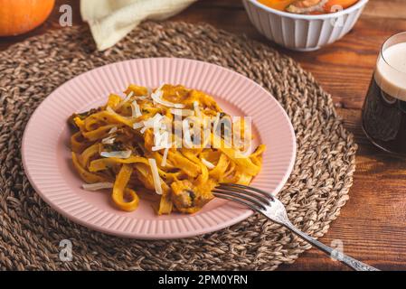 Pâtes de fettuccine à la citrouille et sauce à la crème sure aux champignons, garnies de parmesan râpé Banque D'Images