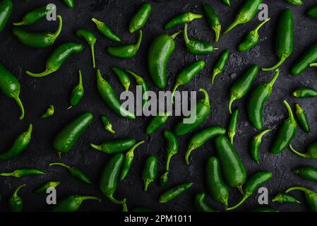 Fond de Peppers de Jalapeno vert mûr sur une surface en béton foncé Banque D'Images