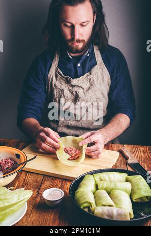 Homme cuisant des rouleaux de chou farcis à la viande hachée dans la cuisine Banque D'Images