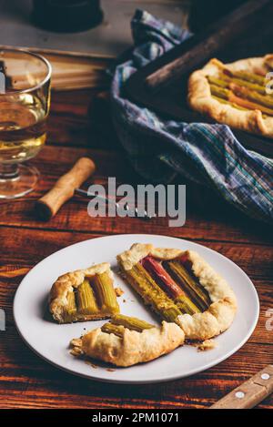 Tranches de mini-galette de rhubarbe sur plaque blanche avec verre de vin blanc Banque D'Images