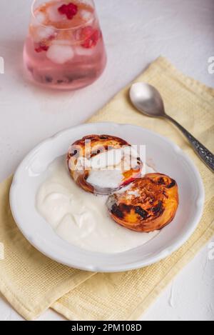 Pêches rôties au four servies avec du miel et de la crème fouettée épaisse sur l'assiette Banque D'Images