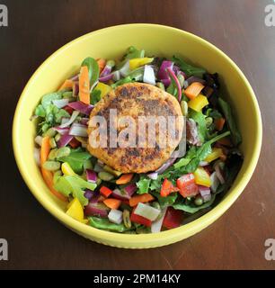 salade fraîche au saumon, patty de saumon poêlée avec des légumes verts frais dans un plat jaune et fond plat Banque D'Images