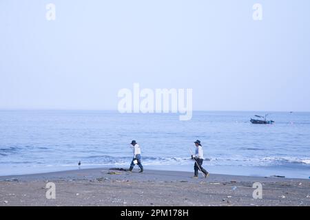 Deux hommes qui marchent sur une plage à Ancon Lima Pérou nettoyant le rivage après un déversement d'hydrocarbures Banque D'Images