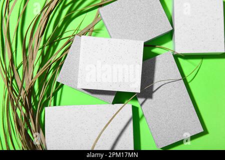 Podiums en plâtre décoratifs et herbe sèche sur fond vert Banque D'Images