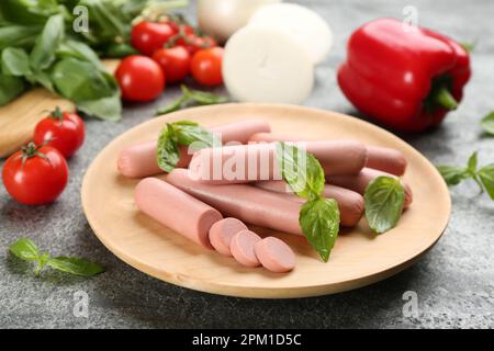 Saucisses végétariennes fraîches, crues, avec basilic et légumes sur table grise Banque D'Images