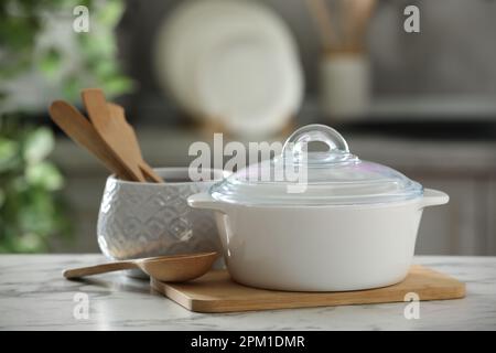 Des casseroles en céramique et des ustensiles de cuisine sont placés sur une table en marbre blanc dans la cuisine Banque D'Images